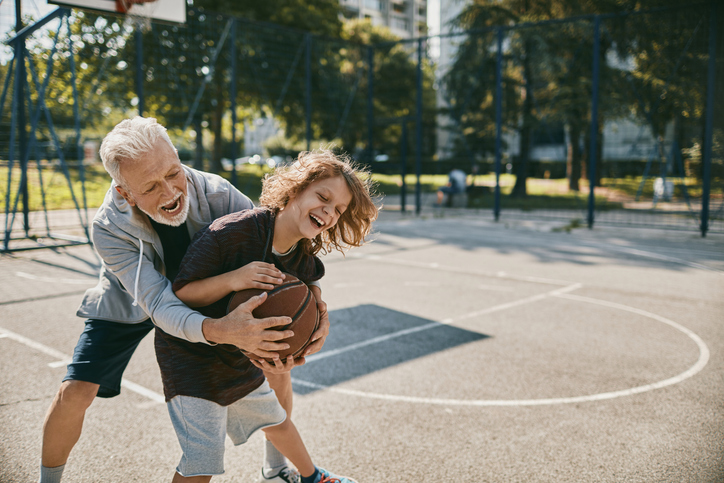 older person playing basketball with a younger person