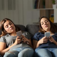 young women lounging on couch on phones